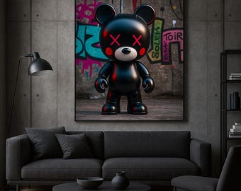 May include: A framed artwork featuring a glossy black bear figure with red 'X' eyes and rosy cheeks. The bear stands against a graffiti-covered concrete wall. The artwork is displayed above a black sofa in a modern living room setting.