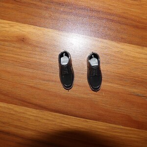 K&ouml;nnte beinhalten: Zwei schwarze Lederschuhe mit Schn&uuml;rsenkeln. Die Schuhe befinden sich auf einer Holzoberfl&auml;che.