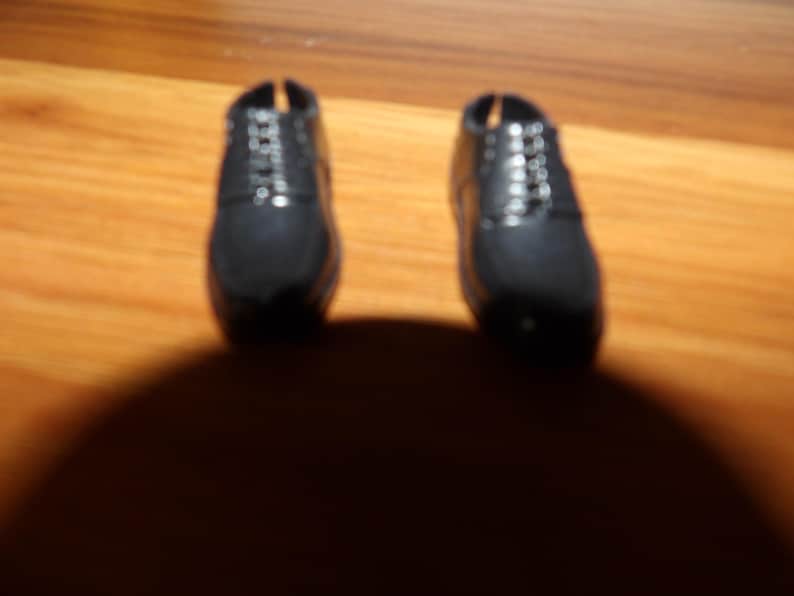 K&ouml;nnte beinhalten: Ein Paar schwarze Lederschuhe mit Schn&uuml;rsenkeln. Die Schuhe sind abgenutzt und haben eine abgewetzte Optik.