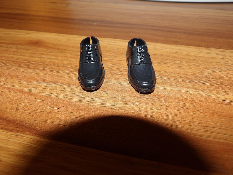 K&ouml;nnte beinhalten: Ein Paar schwarze Lederschuhe mit Schn&uuml;rsenkeln. Die Schuhe haben eine abgerundete Spitze und einen niedrigen Absatz.