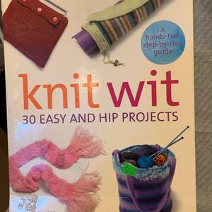 May include: A book titled "knit wit" with the subtitle "30 easy and hip projects." The cover features examples of knitting projects, including a red knitted case, a striped yoga mat holder, and a pink scarf. A blue and purple yarn basket is also shown.