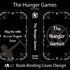 May include: Black book cover design for "The Hunger Games" with white text and illustrations. The front cover features the text "May the odds be ever in your favor" and a silhouette of a person with a bow and arrow.