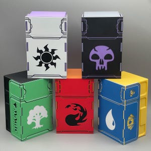 Könnte beinhalten: Eine Sammlung farbenfroher, lasergeschnittener Kartenaufbewahrungsboxen. Jede Box zeigt ein einzigartiges Symbol und Farbschema, darunter Weiß mit Sonne, Schwarz mit Totenkopf, Grün mit Baum, Rot mit Flammen und Blau mit einem Wassertropfen. Für Sammelkartenspiele.