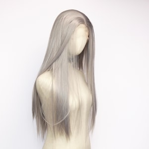 Puede incluir: Una peluca larga de color gris plateado con encaje frontal se muestra en un maniquí. La peluca presenta cabello liso y fluido con sutiles variaciones de tono, creando una apariencia natural. El maniquí está sobre un fondo blanco liso.