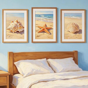 May include: Five rectangular framed wall art prints featuring coastal scenes with a hermit crab, a large spiral seashell, an orange starfish, a white scallop shell, and a brown crab, all displayed on a light blue wall above a wooden bed frame.