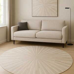 Könnte beinhalten: Ein neutrales Wohnzimmer mit beigem Sofa, großem quadratischem Kunstwerk und rundem Teppich mit Sonnenstrahl-Design. Eine schwarze Stehlampe steht rechts. Der Durchmesser des Teppichs beträgt ca. 244 cm.