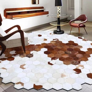 Può includere: Tappeto in pelle di mucca a forma esagonale con un mix di toppe bianche, marroni e beige. Il tappeto è posizionato su un pavimento piastrellato ed è circondato da mobili, tra cui un'unica sedia in legno e un tavolino rotondo.