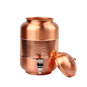 May include: A copper water dispenser with a hammered texture on the middle section. The dispenser has a spigot and a lid with a small handle. The overall design is a shiny, metallic finish, suitable for home use.