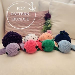 May include: A collection of handmade crochet turtle toys in various colors, including purple, pink, green, and blue. The turtles have black eyes and are arranged in a row. The image also includes text that says "PDF PATTERN BUNDLE".