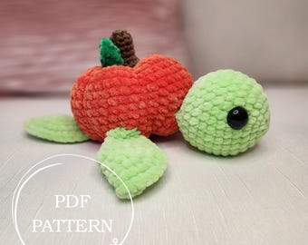 May include: A handmade crochet turtle with a pumpkin body. The turtle has a bright orange body, green leaves, and a light green head with a black eye. The text "PDF PATTERN" is in a white circle.