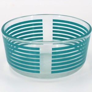 May include: A clear glass bowl with a teal horizontal stripe design. The stripes wrap around the bowl, with vertical teal stripes creating a cross pattern. The bowl is round and sits on a white surface.