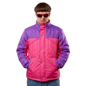 May include: A color-blocked puffer jacket featuring a vibrant purple upper section and a bright pink lower section. The jacket has a high collar, a front button closure, and long sleeves with elastic cuffs. The design includes a yellow inner lining.