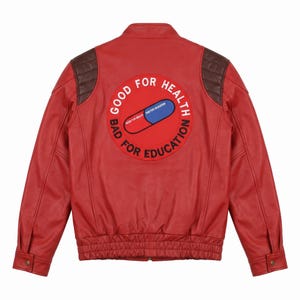 May include: A red leather jacket featuring dark brown quilted shoulder panels and a large circular patch on the back. The patch displays a red and blue pill graphic with the white text GOOD FOR HEALTH and the black text BAD FOR EDUCATION.