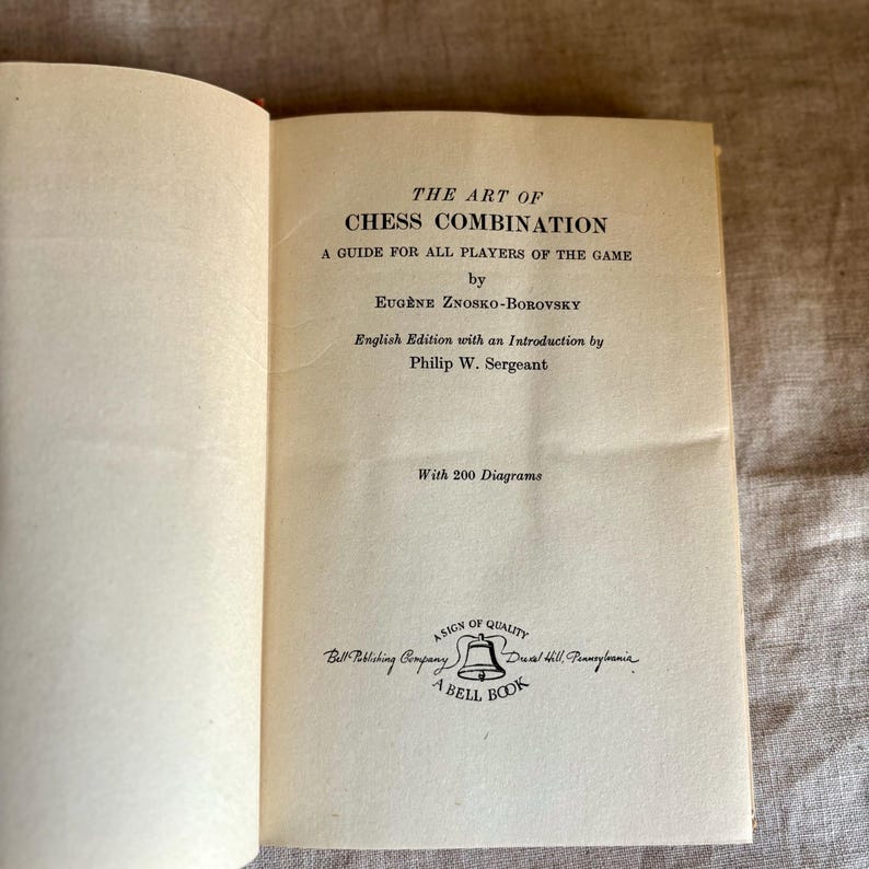 May include: Open book titled "THE ART OF CHESS COMBINATION" by Eug&egrave;ne Znosko-Borovsky. The book is an English edition with an introduction by Philip W. Sergeant. The book cover is off-white with black text. The book is a guide for all players of the game.