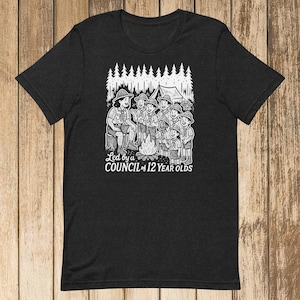 Könnte beinhalten: Dunkelgraues T-Shirt mit einer Schwarz-Weiß-Illustration von Pfadfindern um ein Lagerfeuer, ein Zelt und Bäume. Der Text lautet "Led by a COUNCIL of 12 YEAR OLDS".