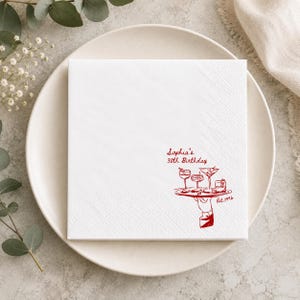 May include: A square white paper napkin featuring a red printed illustration of a hand holding a serving tray with four cocktail glasses. The text reads "Sophia's 30th Birthday" and "Est. 1996" in a red script font, centered on the lower right side.