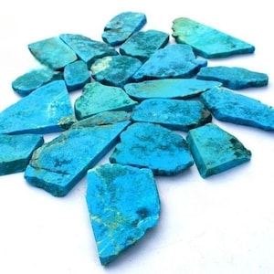 Peut inclure: Une collection de tranches de pierre turquoise plates et de formes irrégulières, présentant des nuances vibrantes de bleu vif et de sarcelle avec des veines de matrice sombres naturelles. Ces pièces fines et polies sont disposées en grappe.