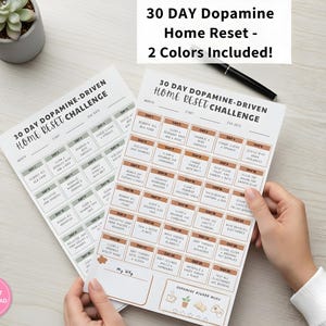 May include: Two printable 30-day home reset challenge sheets. The sheets have a grid layout with daily tasks and the text "30 DAY Dopamine-Driven Home Reset Challenge." The text "2 Colours Included!" is also visible.