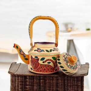 May include: A decorative yellow teapot with a matching lid, featuring a hand-painted design of a tiger, birds, and leaves. The teapot has a curved spout and a yellow handle. The lid is off to the side, revealing the interior.