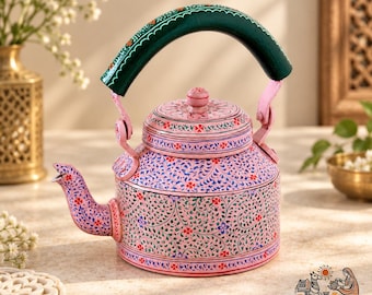 May include: A light pink metal tea kettle featuring a dark green handle and a hand-painted floral pattern in blue, green, and red. The kettle has a matching lid with a small knob and a curved spout, all decorated with intricate vine motifs.
