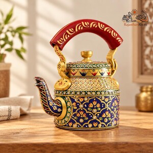 May include: A decorative metal kettle featuring a vibrant hand-painted floral pattern in blue, gold, and red. The handle is solid red with gold detailing, and the body is adorned with intricate gold filigree, small white dots, and a spout.