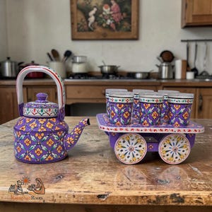 May include: A purple metal teapot and a matching set of six small glasses arranged on a purple four-wheeled cart. Both the teapot and glasses feature a hand-painted floral pattern in yellow, green, and white. The cart has decorative wheels.