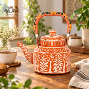 May include: A vibrant orange metal tea kettle featuring intricate white floral and architectural patterns. The handle is painted with orange, green, and yellow floral motifs. The spout is decorated with white polka dots, and the lid has a matching knob.