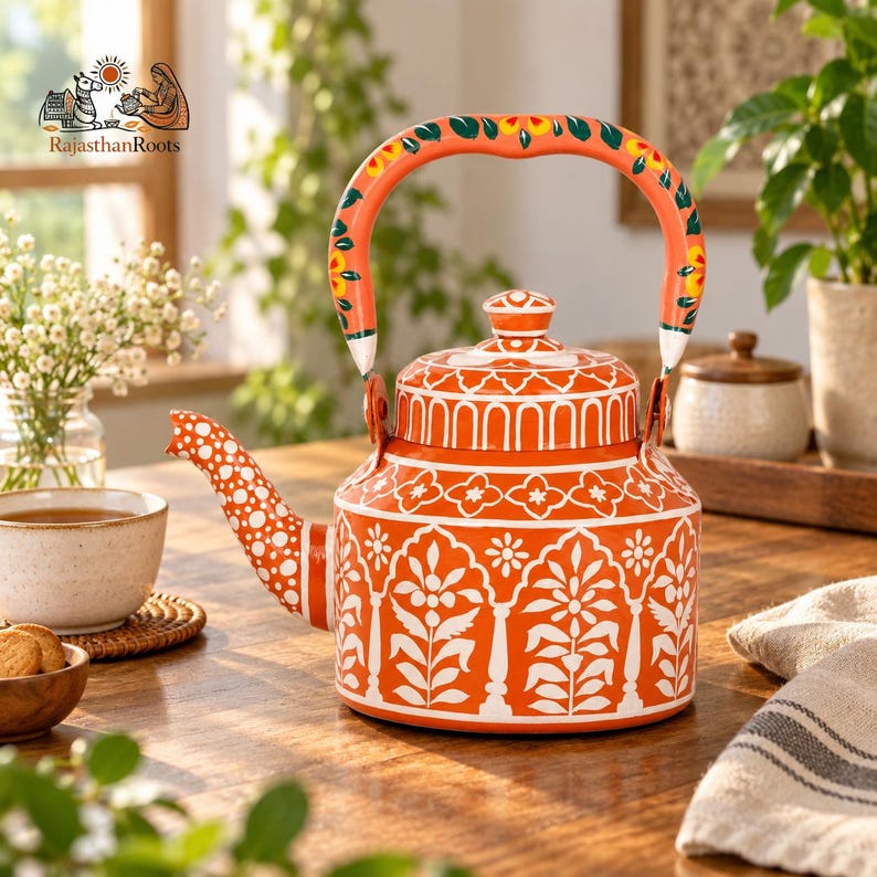 May include: A vibrant orange metal tea kettle featuring intricate white floral and architectural patterns. The handle is painted with orange, green, and yellow floral motifs. The spout is decorated with white polka dots, and the lid has a matching knob.