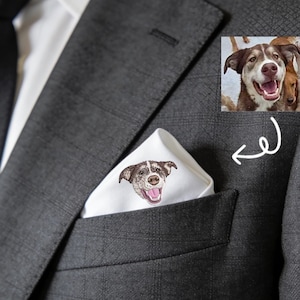 Könnte beinhalten: Ein weißes Einstecktuch mit einem gestickten Hundegesicht lugt aus einer dunkelgrauen Anzugtasche. Der Hund hat braunes und weißes Fell mit einer rosa Zunge. Der Anzug ist dunkelgrau kariert.