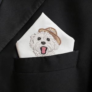 May include: A black suit jacket with a white pocket square featuring an embroidered dog wearing a cowboy hat. The dog has its mouth open, and the pocket square is neatly folded in the jacket pocket.