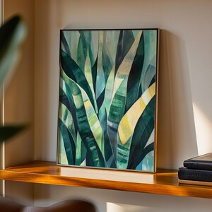 Könnte beinhalten: Ein rechteckiges gerahmtes Wandbild mit einer abstrakten botanischen Illustration aus überlappenden, langen, spitzen Blättern in verschiedenen Schattierungen von dunklem Waldgrün, Salbei, Minze und blassem Gelb, eingefasst in einen dünnen Goldrahmen.