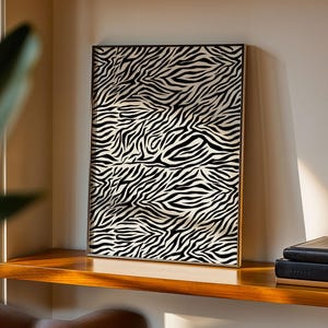 May include: A rectangular framed wall art piece featuring a high-contrast black and white zebra stripe pattern. The print is encased in a thin, metallic frame and displays a repeating, organic, wavy line design across the entire surface area.