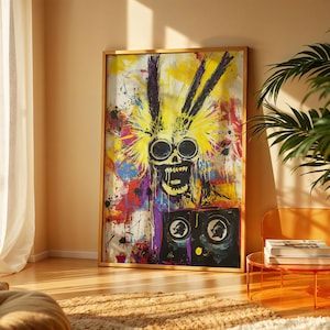 May include: Abstract art print featuring a skull with large, round eyes and an open mouth, rendered in black against a vibrant background of yellow, purple, and red paint splatters. The artwork is framed in a wooden frame and leans against a wall.
