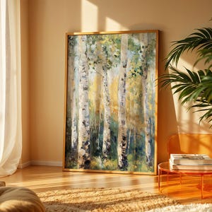 May include: A framed art print showing a forest scene with birch trees. The painting uses greens, yellows, and whites, with a golden frame. The artwork is displayed in a well-lit room with a plant and modern furniture.