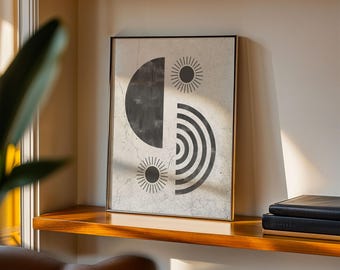 May include: Abstract art print in a gold frame. The artwork features a black and white geometric design with a half-circle, sunbursts, and concentric arcs. The print is displayed on a wooden shelf with books.