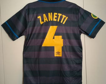 May include: A navy blue and purple striped soccer jersey with the name "ZANETTI" and the number "4" in yellow. The jersey has blue accents on the sleeves and collar, and the Umbro logo is visible.