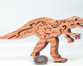 May include: A brown wooden dinosaur puzzle featuring interlocking pieces that form the shape of a raptor. The dinosaur has a small black eye detail and is positioned next to a silver United States Mercury dime for a clear sense of scale.