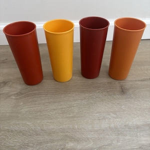 Könnte beinhalten: Ein Set aus drei Keramikbechern mit gesprenkelter, matter Oberfläche. Die Becher sind in Creme-, Hellgrau- und Dunkelgrautönen gehalten. Jeder Becher hat ein schlichtes, minimalistisches Design.