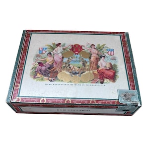 May include: Rectangular cigar box with a detailed, vintage design. The box features illustrations of classical figures, gold accents, and the text "Montesquille" and "Robusto Largo". The box is green, red, and white.