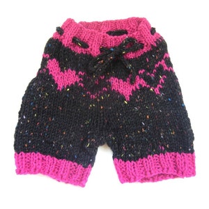 Puede incluir: Pantalones cortos de punto negro y rosa con un estampado moteado de colores. Los pantalones tienen una cintura con cordón.