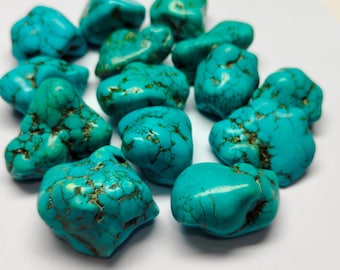 May include: A collection of turquoise gemstones. The stones are a vibrant blue-green color with dark brown veining. The gemstones are irregularly shaped and appear to be polished. The image is taken on a white background.