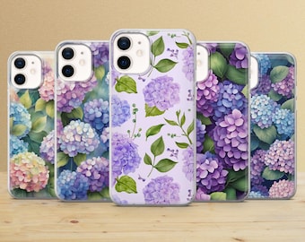 May include: Five clear phone cases with floral designs featuring hydrangea blooms in shades of purple, blue, and pink. The cases are arranged on a wooden surface, showcasing the variety of floral patterns.