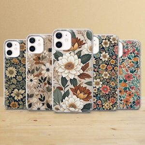 May include: Five floral-patterned phone cases. The designs feature various flower arrangements in colors like white, brown, orange, and green. The cases are displayed on a wooden surface.