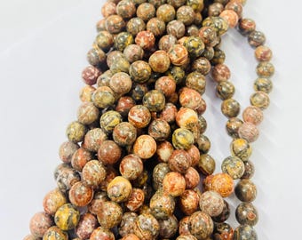 May include: Strands of round gemstone beads in shades of brown, tan, yellow, and red. The beads have a mottled pattern and are strung together, suggesting they are for jewelry making or crafts.
