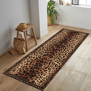Könnte beinhalten: Ein rechteckiger Teppich mit Leopardenmuster und schwarzem Rand. Der Teppich weist ein braunes und schwarzes Fleckenmuster auf, das dem Fell eines Leoparden ähnelt. Der Teppich liegt auf einem Holzboden.