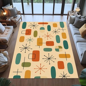 Könnte beinhalten: Ein beiger Teppich mit modernem Design aus der Mitte des Jahrhunderts. Der Teppich zeigt geometrische Formen in Türkis, Orange, Gelb und Olivgrün sowie schwarze Sternen- und Liniendetails. Der Teppich liegt auf einem Holzboden.