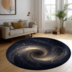 Könnte beinhalten: Ein runder Teppich mit Galaxien-Design. Der Teppich hat einen dunkelblauen Hintergrund mit einem wirbelnden Muster aus goldenen und weißen Sternen, das einen kosmischen Effekt erzeugt. Der Teppich liegt auf einem Holzboden in einem Wohnzimmer.