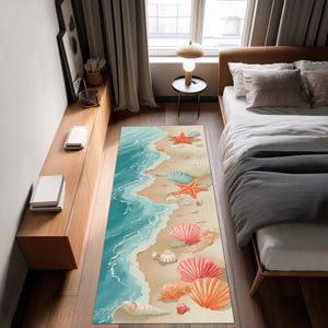Peut inclure: Un tapis rectangulaire sur le thème de la plage avec un motif aquarelle. Le tapis représente une plage de sable avec des vagues turquoise, des coquillages et des étoiles de mer dans des tons orange, rose et blanc. Le tapis est placé dans une chambre.