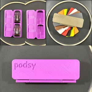 Könnte beinhalten: Eine Sammlung von Vaping-Zubehör, darunter ein lila Etui mit dem Wort "podsy" auf der Oberseite. Das Etui wird offen und geschlossen gezeigt, mit zwei sichtbaren Vaping-Kartuschen. Ein Farbmusterfächer ist ebenfalls enthalten.