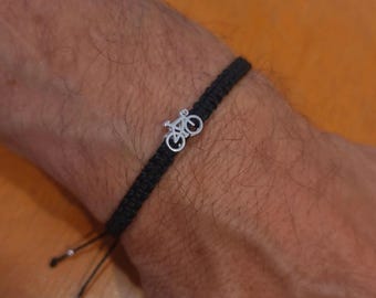 May include: Black braided bracelet with a silver bicycle charm. The bracelet is adjustable with sliding knots. The bicycle charm is a detailed miniature of a bicycle.